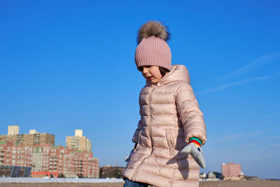 Young girl playing on the beach in winter dressed in a warm coat