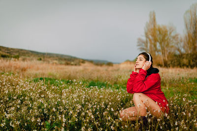 Woman with flowers on field against sky