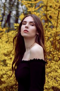 Side view portrait of beautiful woman standing by flowering plant