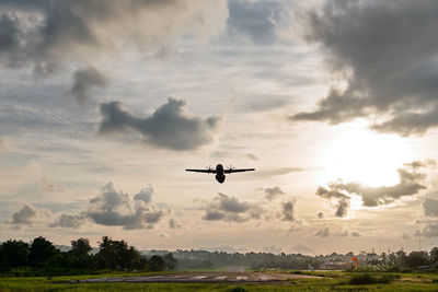 Airplane flying in sky during sunset