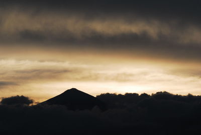 Silhouette of mountain against cloudy sky