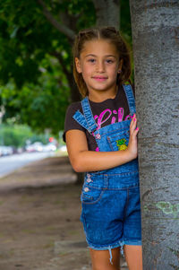 Portrait of smiling girl standing against tree