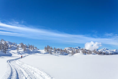 Snow covered landscape against blue sky