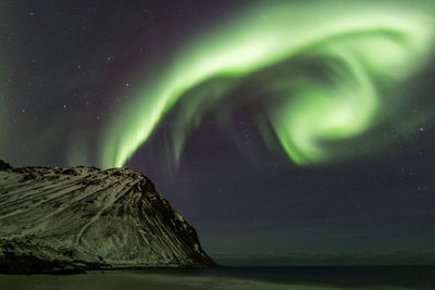 Scenic view of mountain against aurora borealis at night