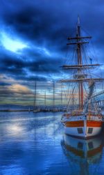 Sailboats in sea against cloudy sky