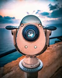 Close-up of coin-operated binoculars by sea against sky