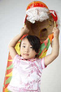 Cute girl holding dragon costume against white background