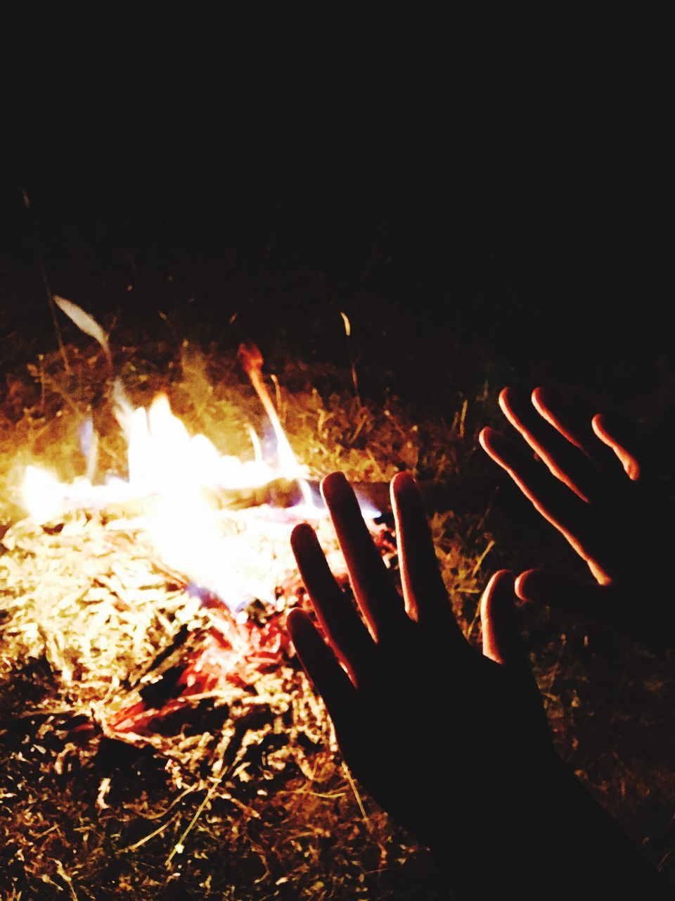 CLOSE-UP OF HANDS BURNING AT NIGHT