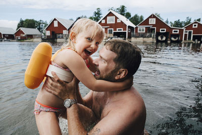 Portrait of cheerful daughter with father in lake during vacations