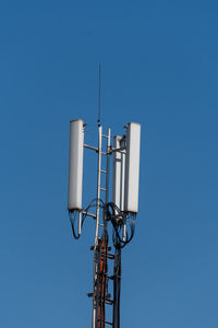 Low angle view of communications tower against blue sky