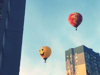 Low angle view of hot air balloons flying against sky in city