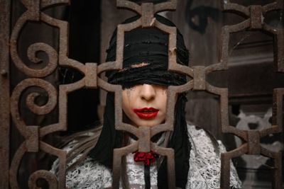 Close-up portrait of young woman in halloween costume behind metal fence