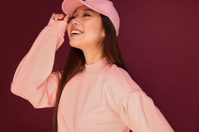 Midsection of woman holding pink while standing against gray background