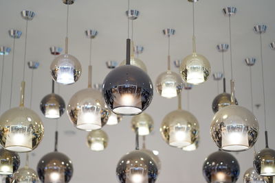 Low angle view of illuminated pendant lights hanging for sale in store