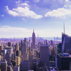 Aerial view of buildings in city against cloudy sky