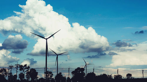 Low angle view of wind turbines against sky