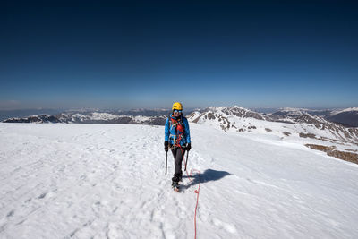 Rear view of person on snowcapped mountain against sky