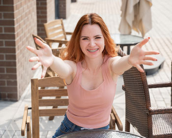 Portrait of young woman sitting on railing