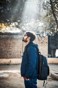 Side view of young man looking at camera