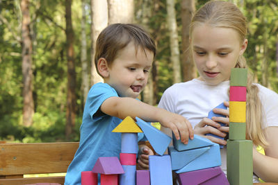 Siblings playing with toy blocks on table