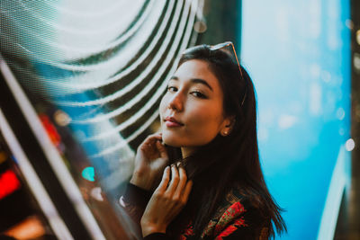 Close-up of young woman standing against illuminated city at night