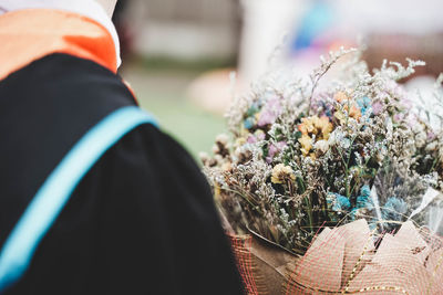 Midsection of person standing by flower bouquet