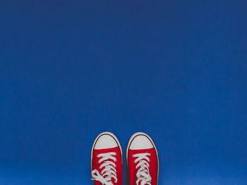 Low section of person standing against blue sky