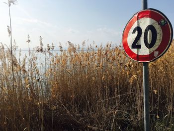 Abandoned speed limit sign by lake against sky