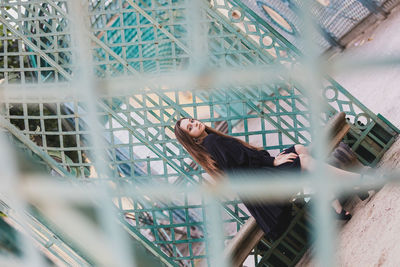 Portrait of woman seen through metal fence