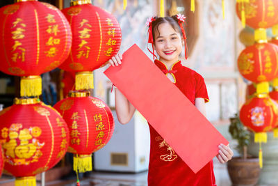 Portrait of smiling woman standing by red lanterns