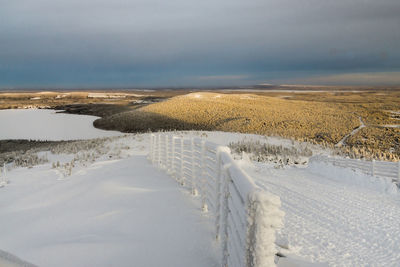 Scenic view of snow covered land against sky