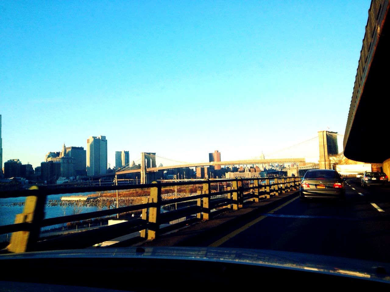 clear sky, architecture, built structure, copy space, building exterior, city, transportation, blue, bridge - man made structure, connection, cityscape, bridge, railing, city life, river, dusk, illuminated, sky, engineering, car