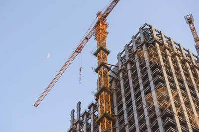 Low angle view of crane against clear sky