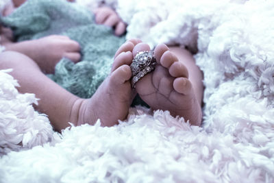 Close-up of baby feet with ring lying on bed