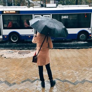 Rear view of man with umbrella walking on street