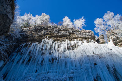 Low angle view of icicles against blue sky
