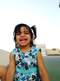 Portrait of cute girl smiling girl against clear sky