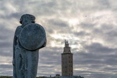 Statue against tower and building against sky