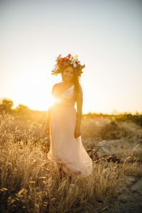 Portrait of young woman on field against clear sky