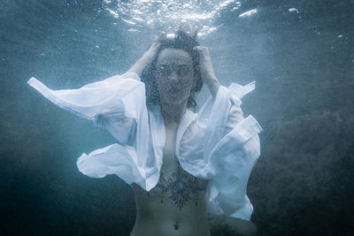 Portrait of young woman swimming underwater in sea