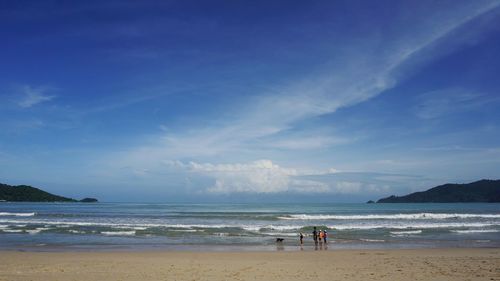 People with dog at beach against sky