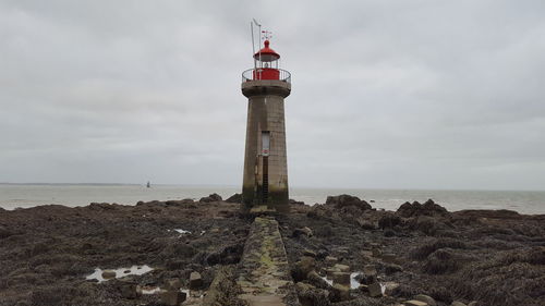 Lighthouse by sea against sky