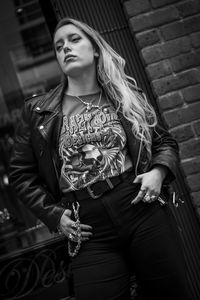 Portrait of young woman standing against wall