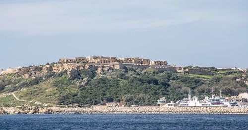 Buildings by sea against sky