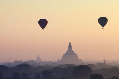 Silhouette hot air balloons flying in sky at sunset