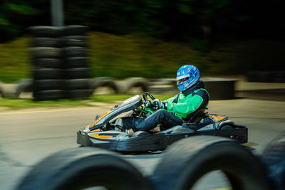 Side view of boy riding motor scooter on road