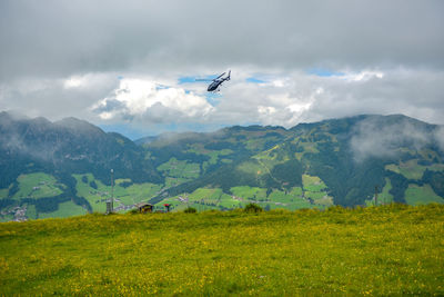 Airplane flying over land and mountains against sky