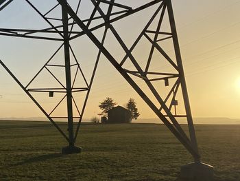 Electricity pylon on field against sky during sunset