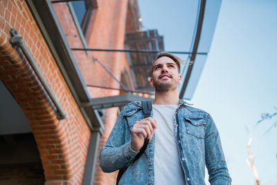 Low angle view of young man standing against building