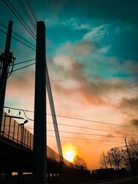 Low angle view of suspension bridge against cloudy sky